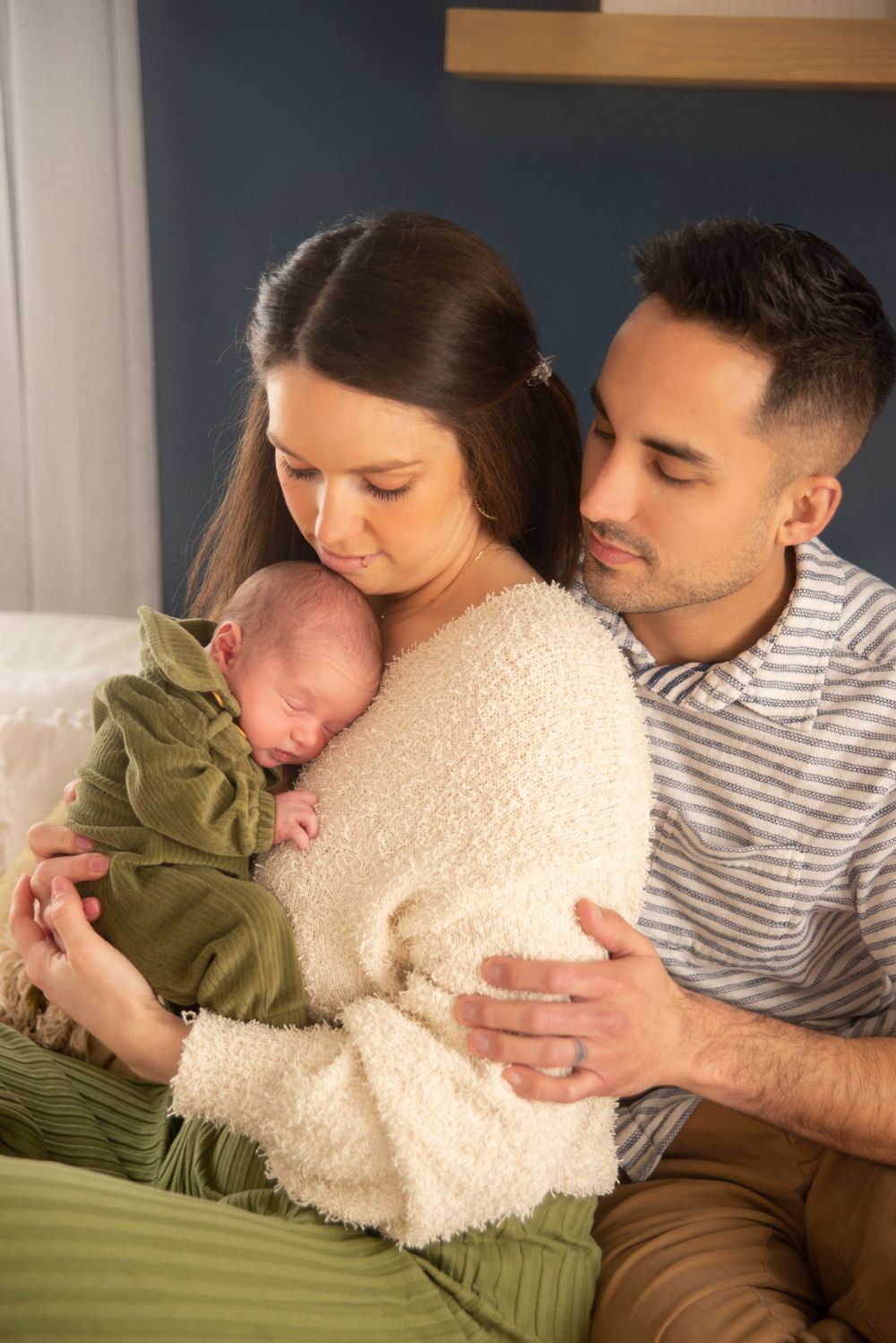 mother holding newborn baby with father behind her