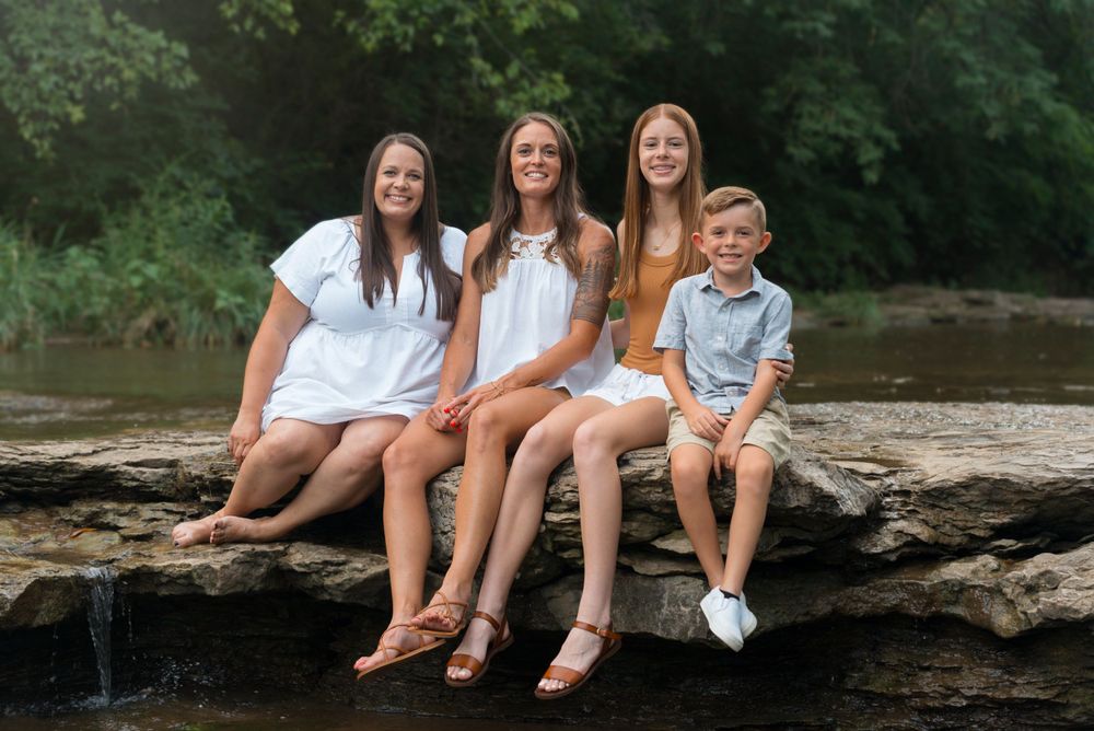 Family of 4 sitting on rocks together