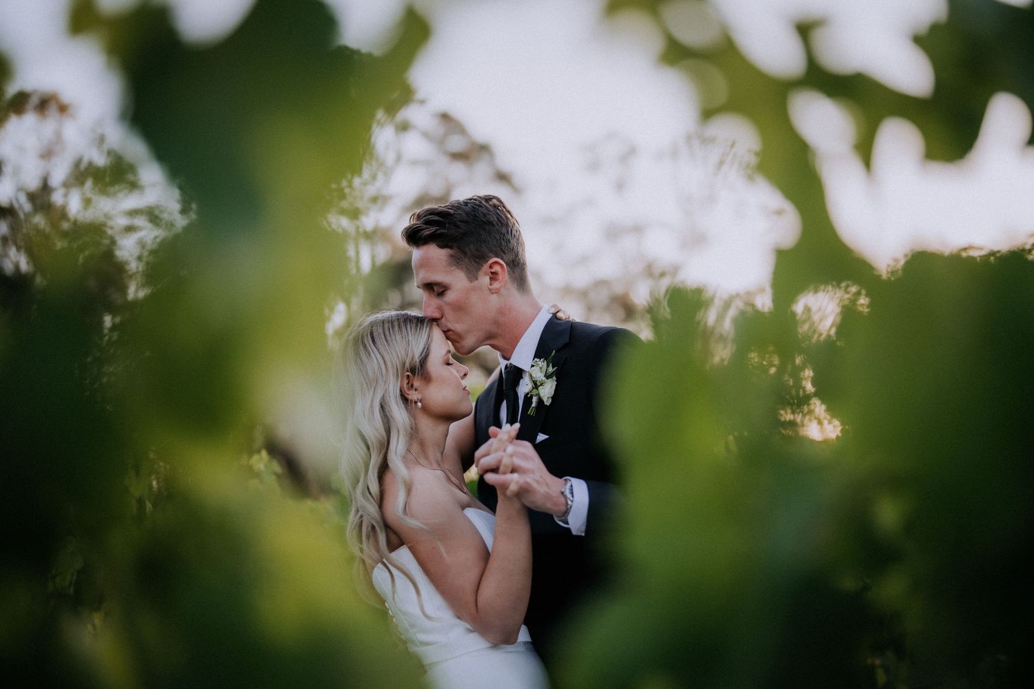 A romantic wedding moment captured through green foliage.