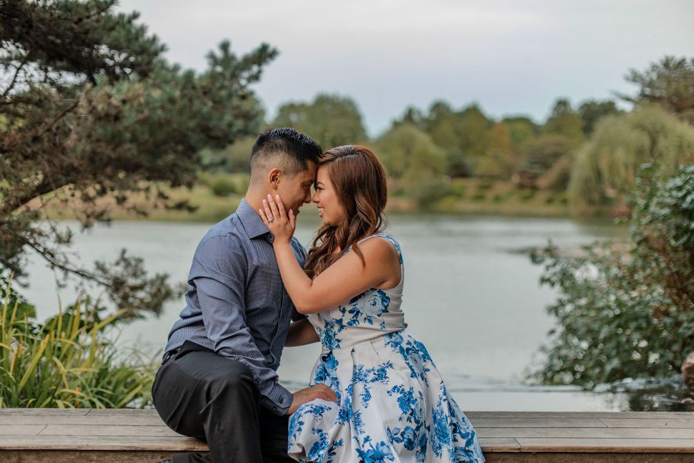 Couple shares intimate moment by lakeside wearing formal attire.