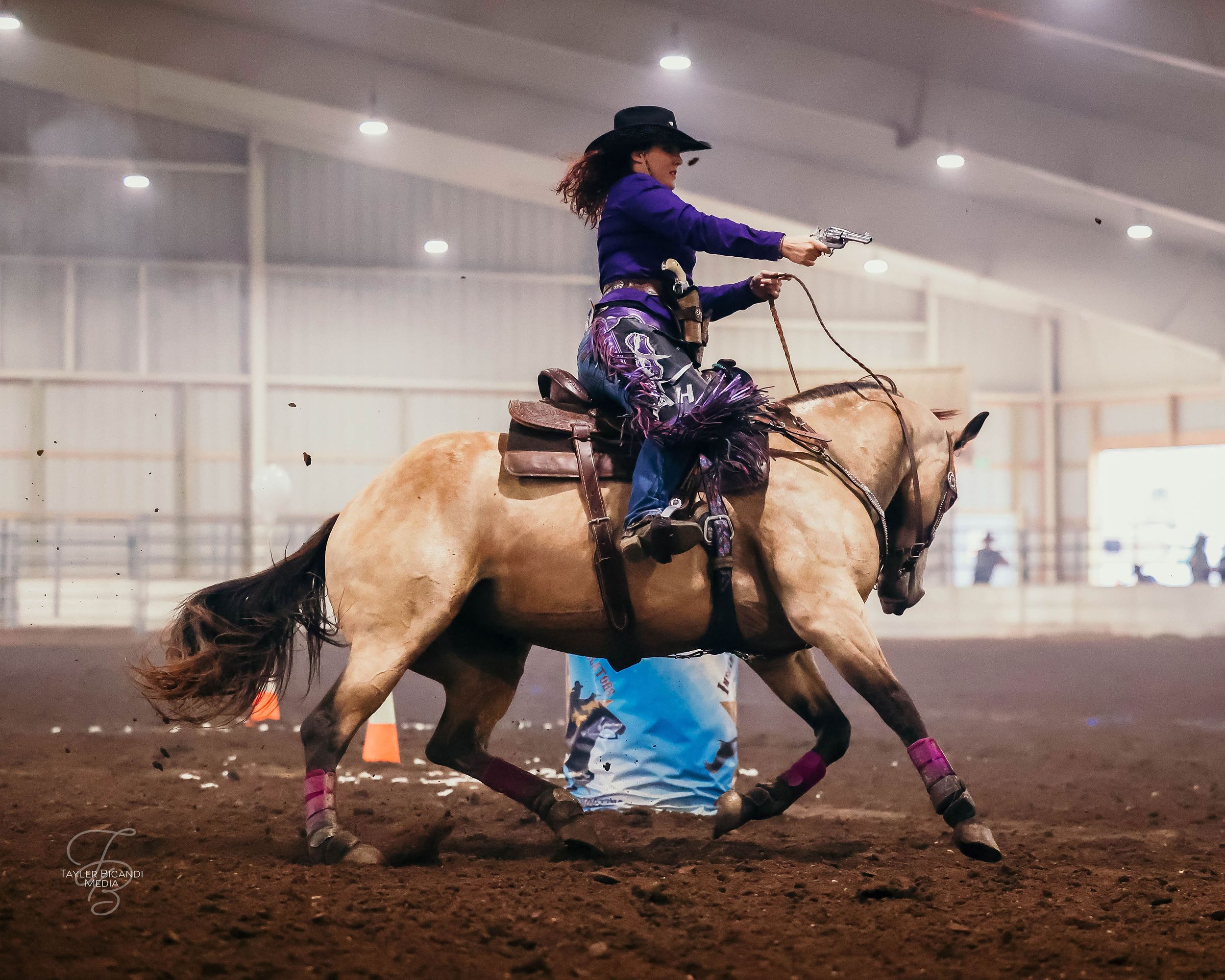 A cowgirl decked in purple, rides a buckskin mare during her CMSA competition.