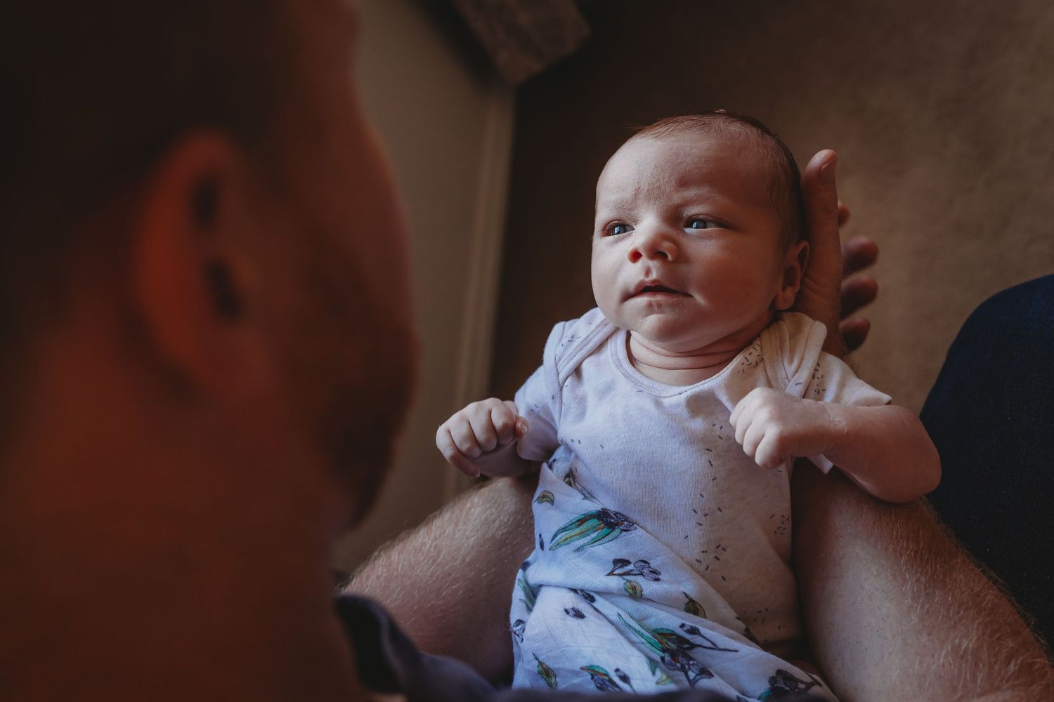 Newborn baby looking up into the eyes of his father