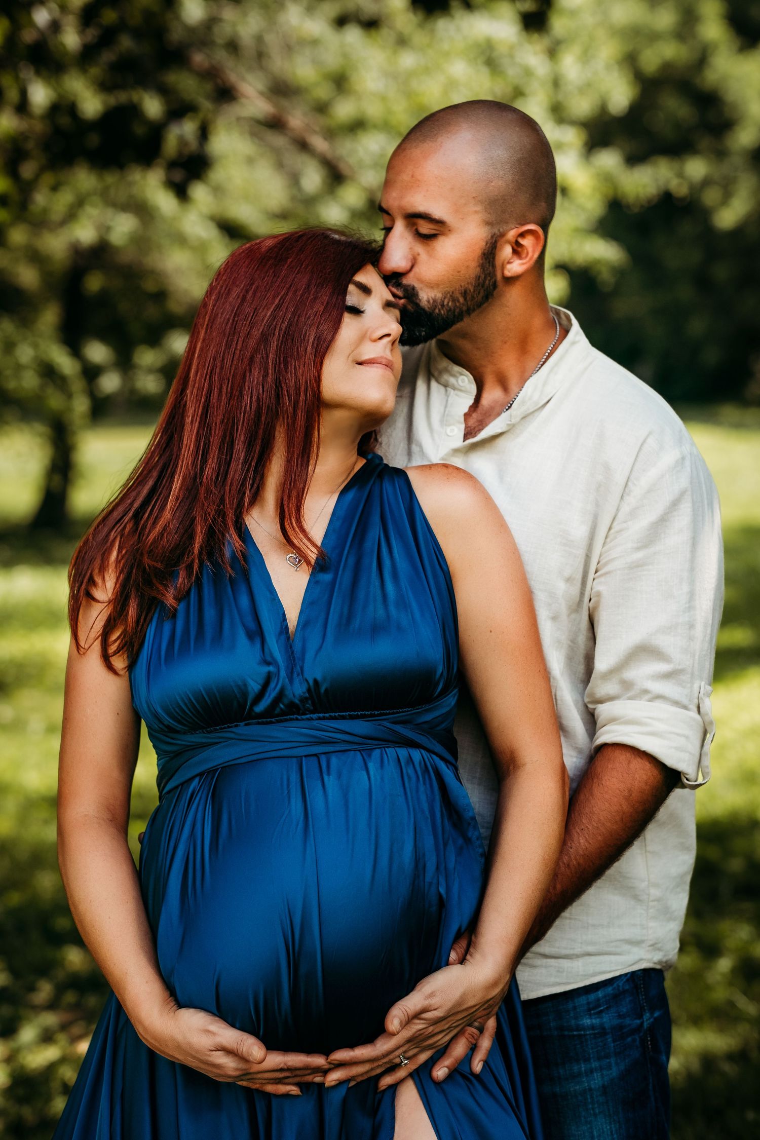 Man kisses woman on the forehead during a maternity photography session in Bentonville, Arkansas.
