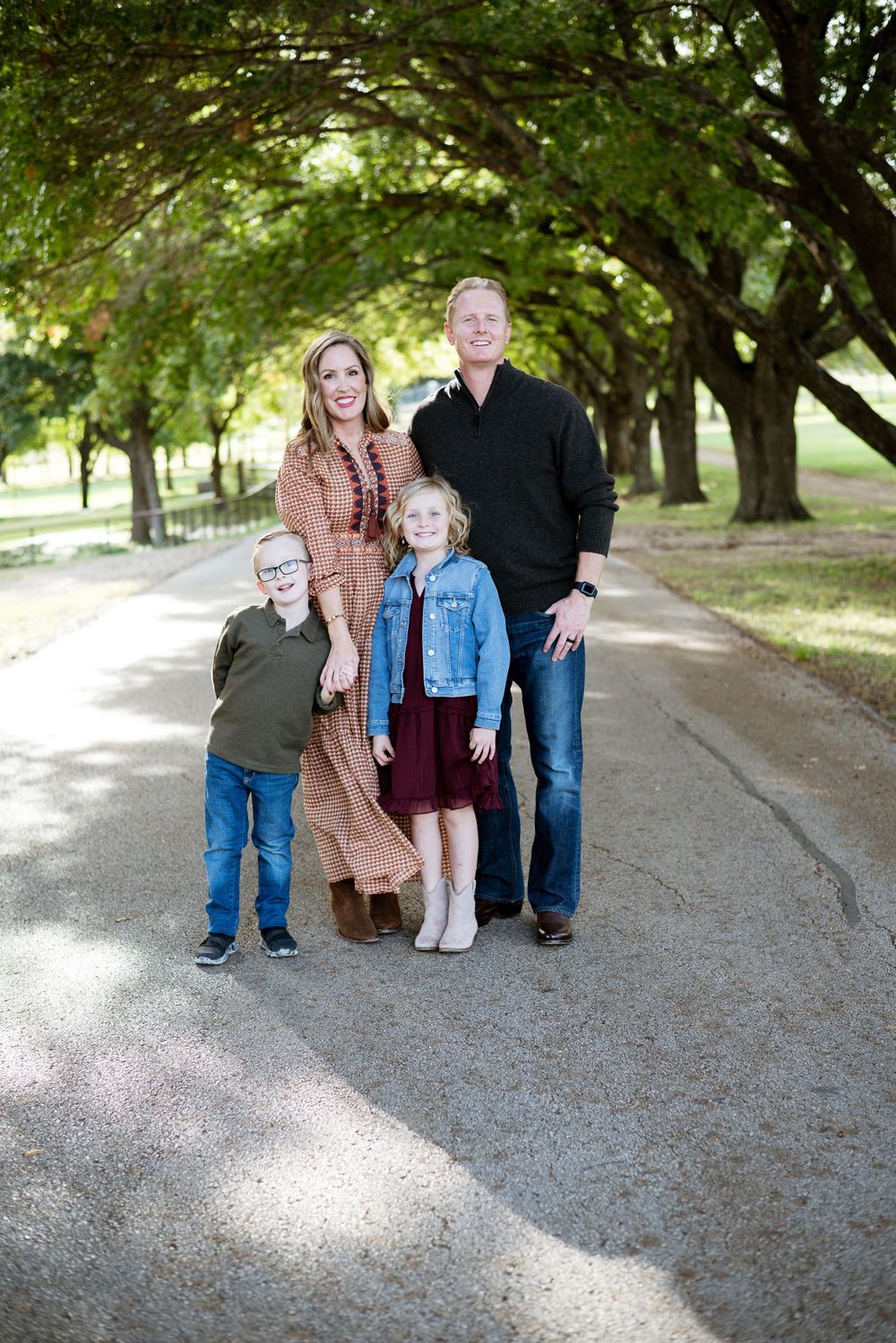 Family portrait series taken on a tree-lined path with dappled sunlight.