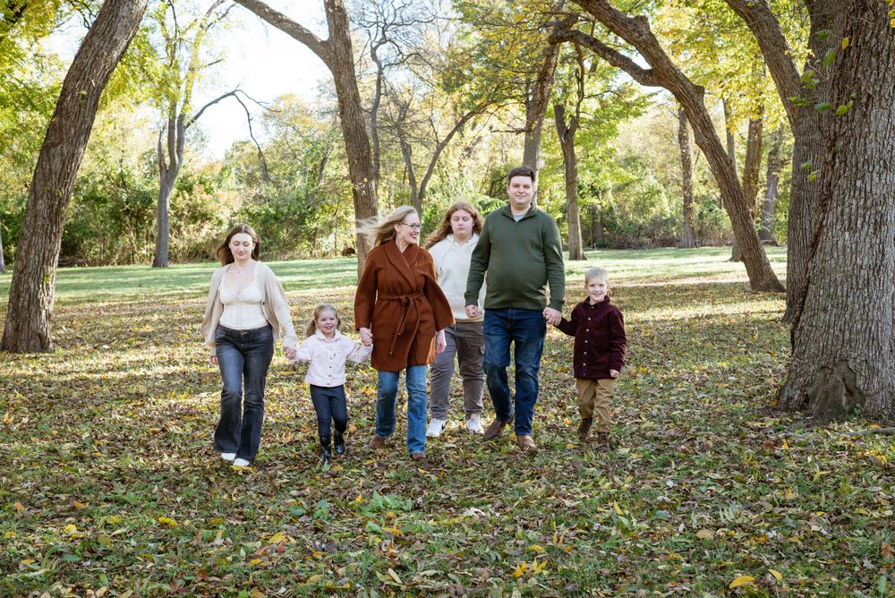 Family group photos in a wooded park setting with fallen autumn leaves.