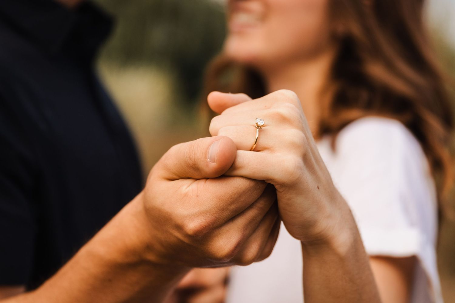 Close-up shot of intertwined hands with an engagement ring.