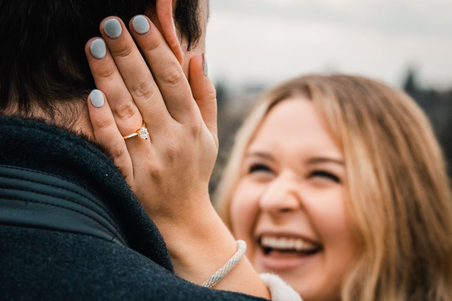 Close-up shot showing engagement ring while sharing a happy moment outdoors.