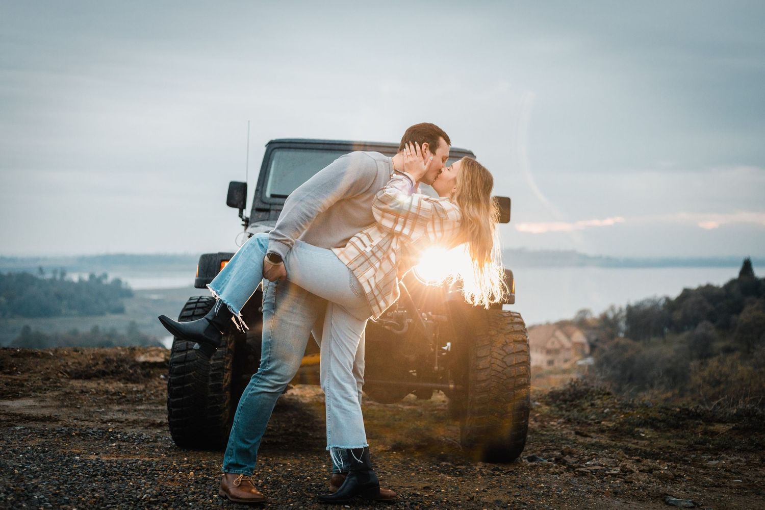 Romantic sunset moment near a vehicle with mountains in the background.