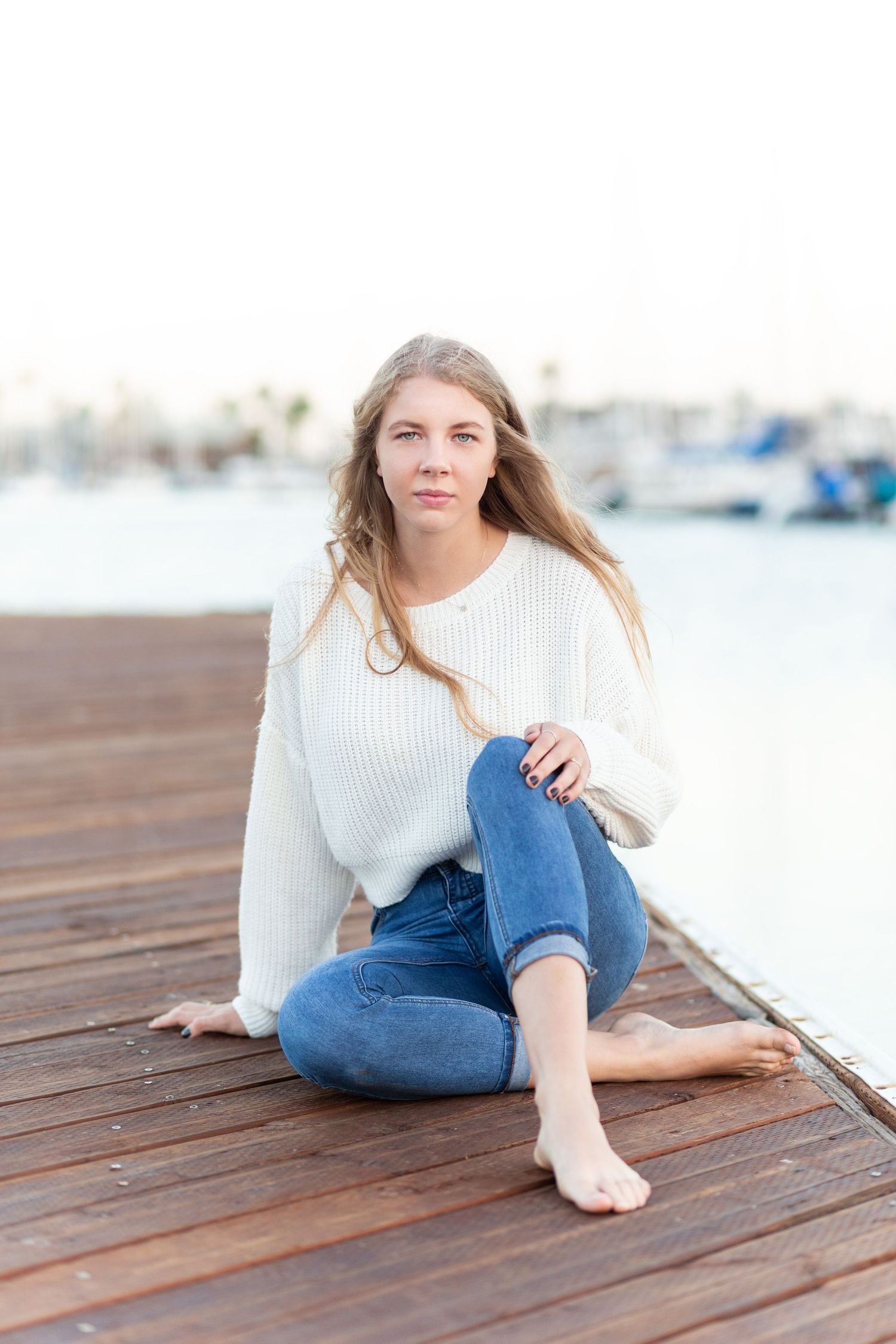 A casual portrait on a wooden dock with boats in the background during golden hour.