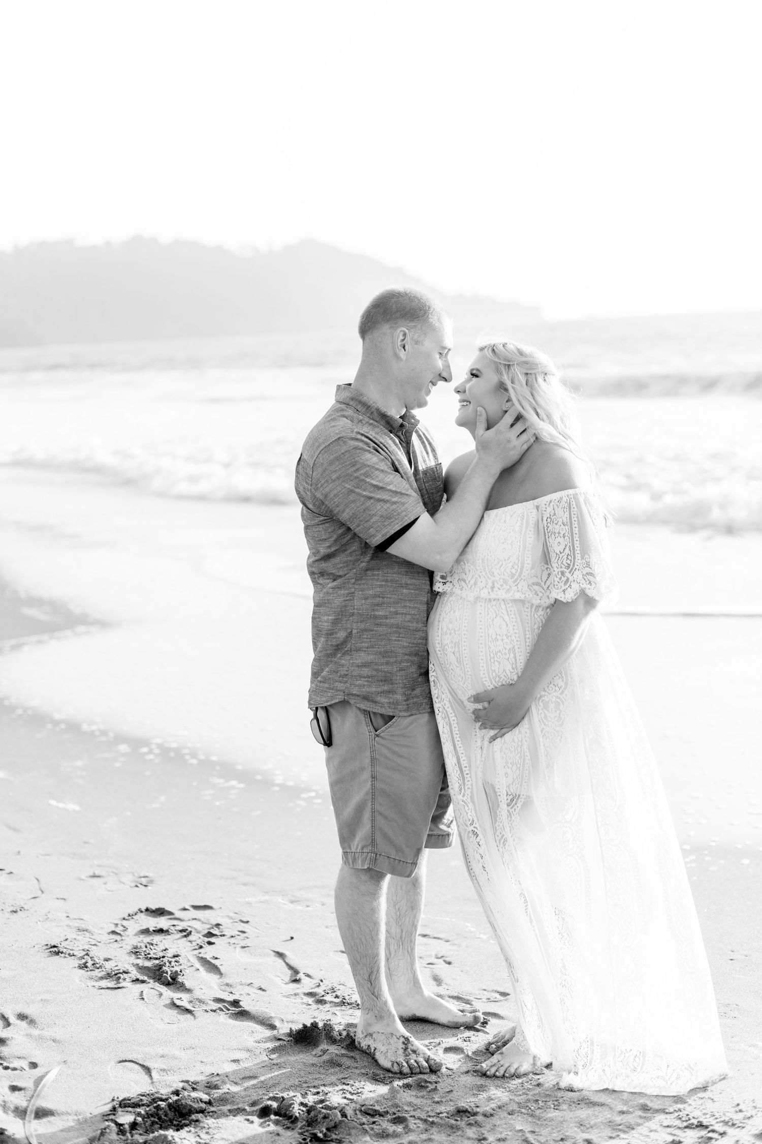 Black and white beach portraits showing tender moments between a couple in formal attire.