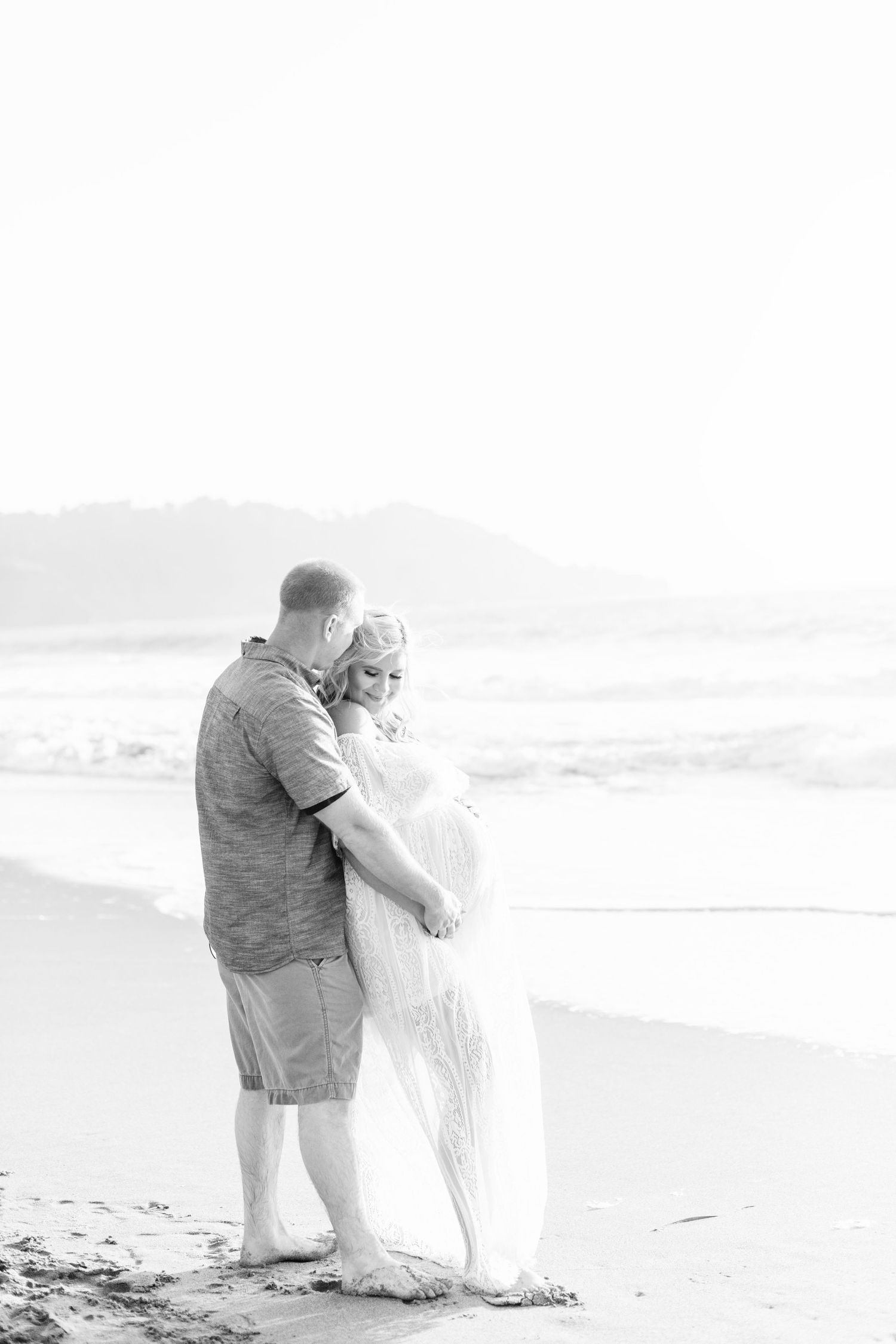 Black and white beach photography capturing romantic moments between a couple.