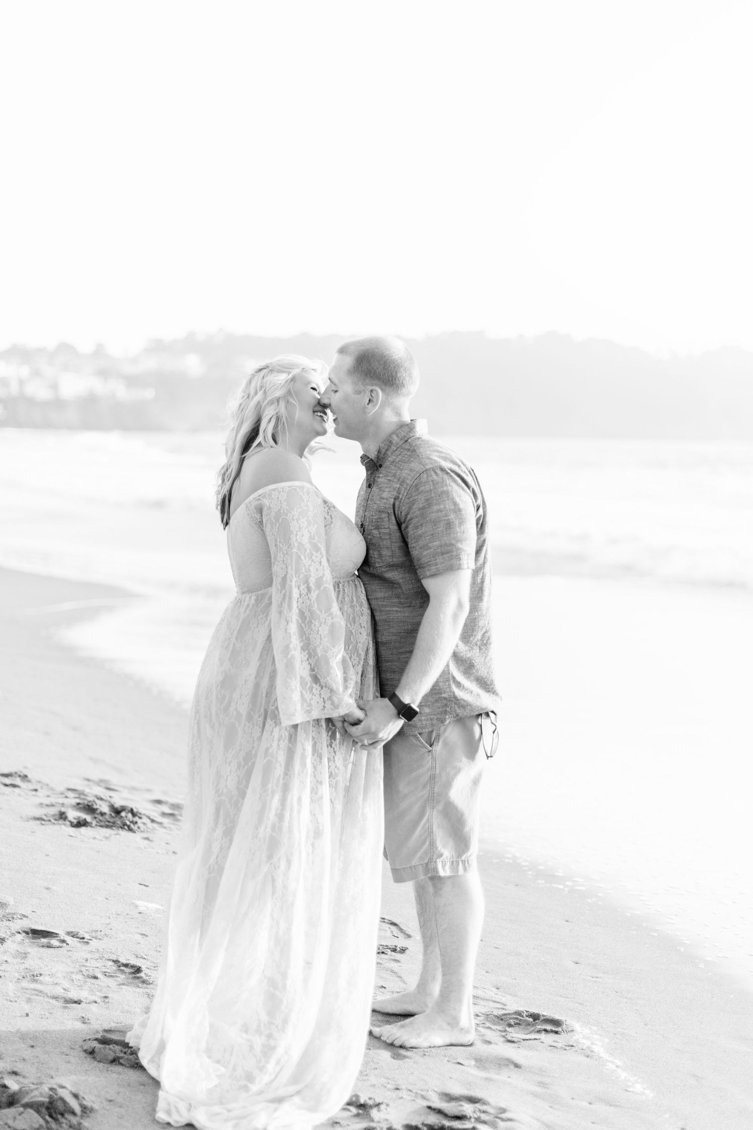 Intimate black and white portrait of couple on foggy beach.