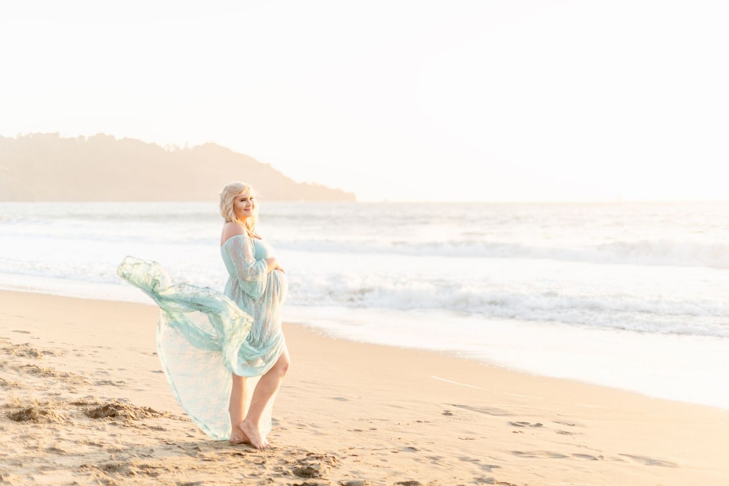Light and airy beach photo with dress flowing in ocean breeze.