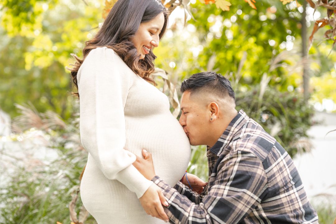 An emotional maternity photo session captured outdoors with autumn foliage in the background.
