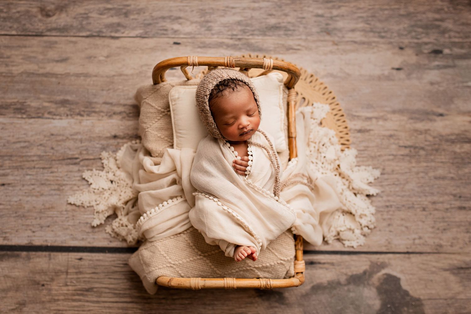 Baby girl wrapped in peach blanket sleeping on small wooden bed on wooden floor in Flowertown Photography Studio in Summerville, SC