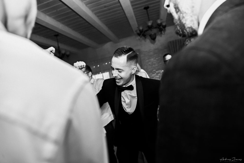 Black and white photo capturing energetic dance moves at a wedding reception.