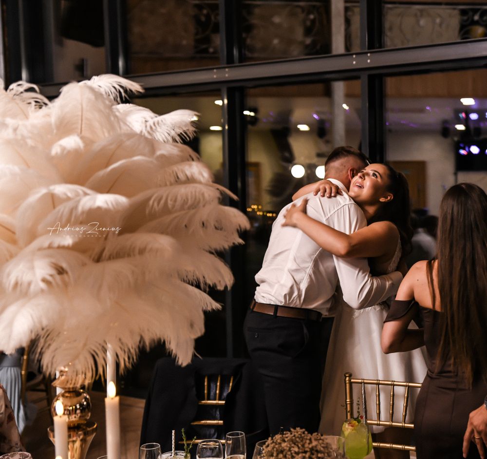 Wedding reception venue decorated with elegant white feather centerpieces and ambient lighting.