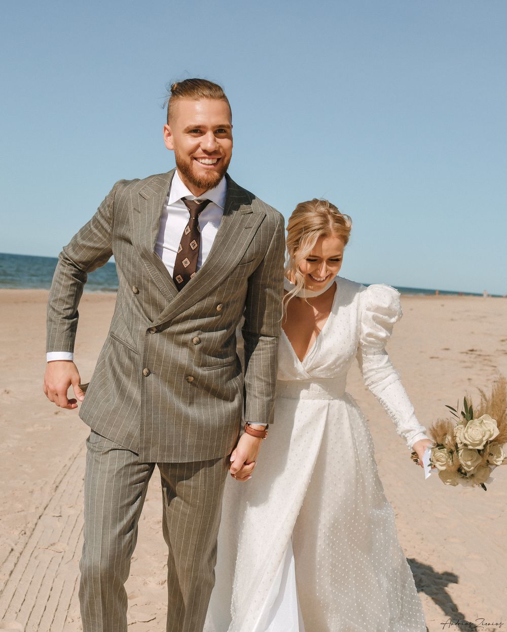 Happy couple shares a candid moment on a beach in wedding attire.