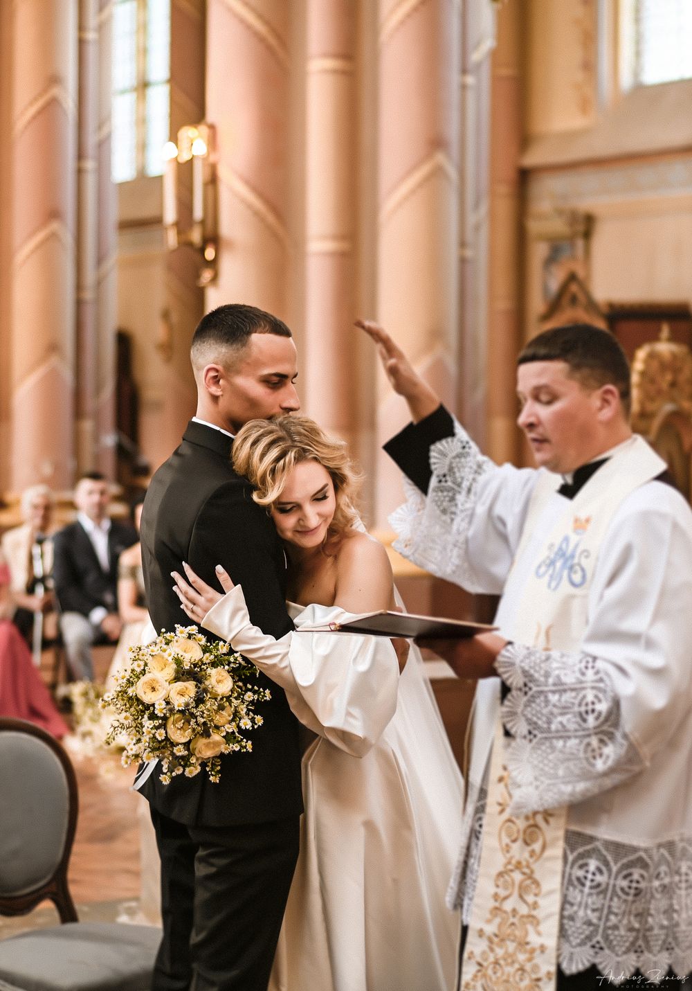 Religious wedding ceremony in progress inside ornate pink-pillared church.