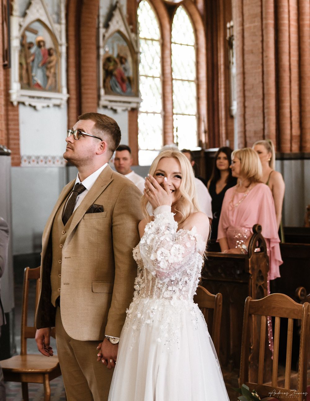 A couple shares an emotional moment during their church wedding ceremony surrounded by stained glass windows.