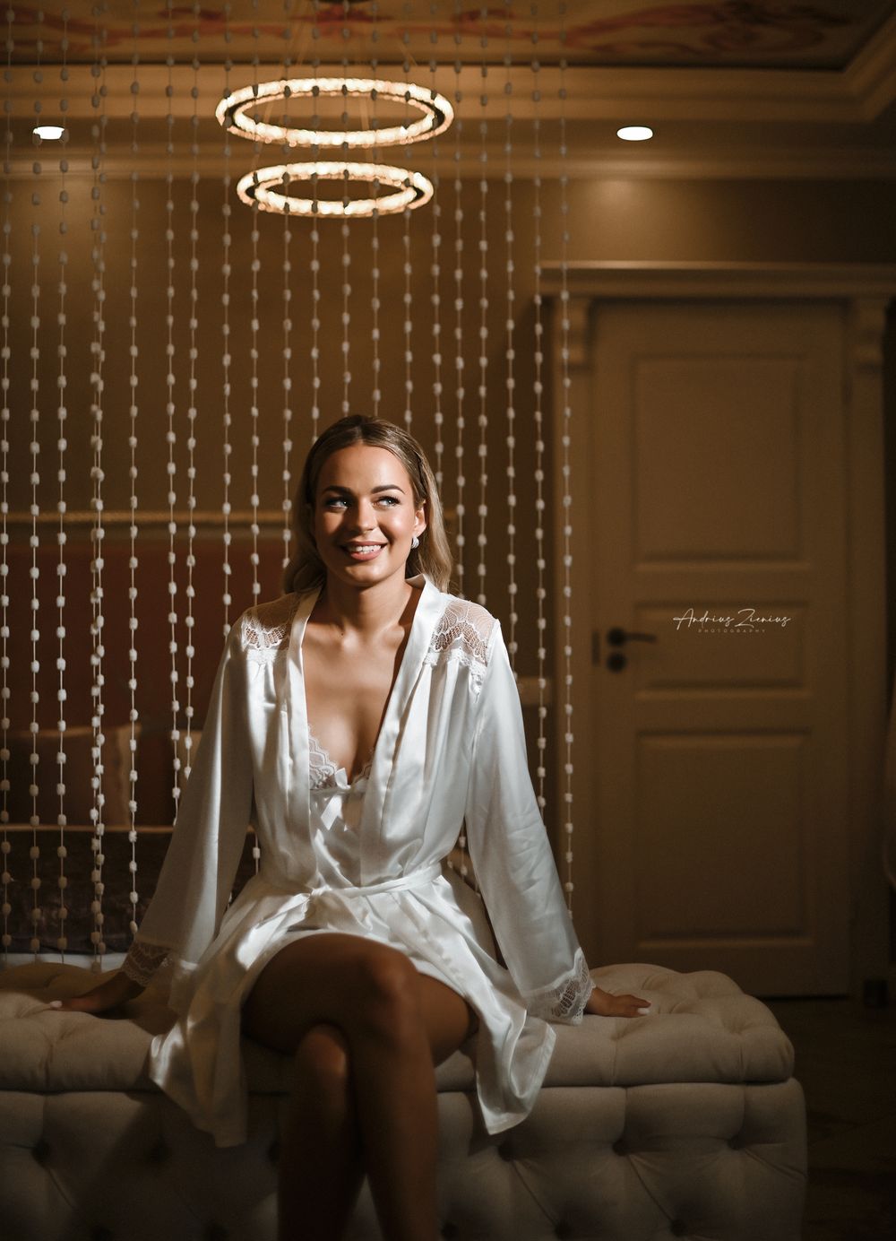 A bridal preparation moment captured under circular chandeliers in an elegant room.