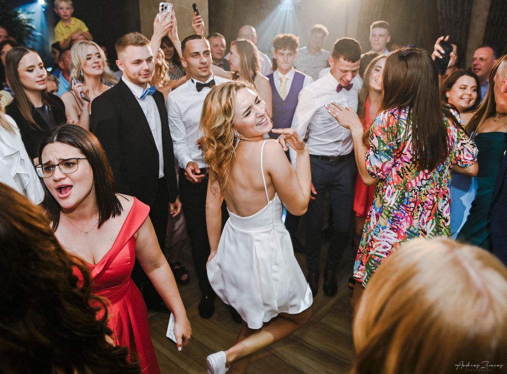 Wedding celebration on dance floor with guests in festive attire.