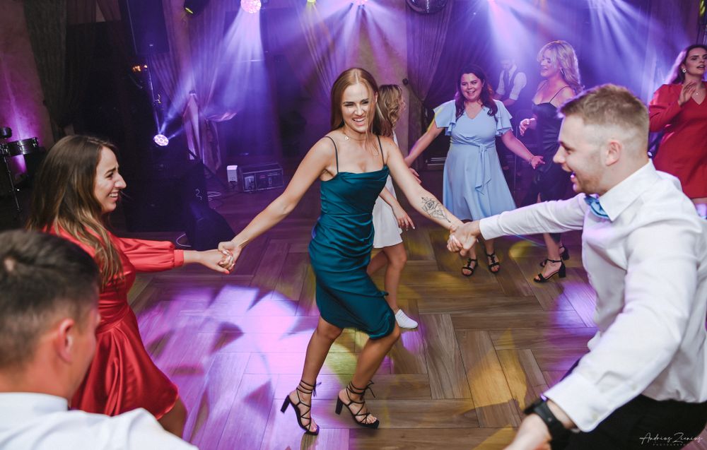 Dynamic dance floor scene with dancers in formal wear under purple stage lights.