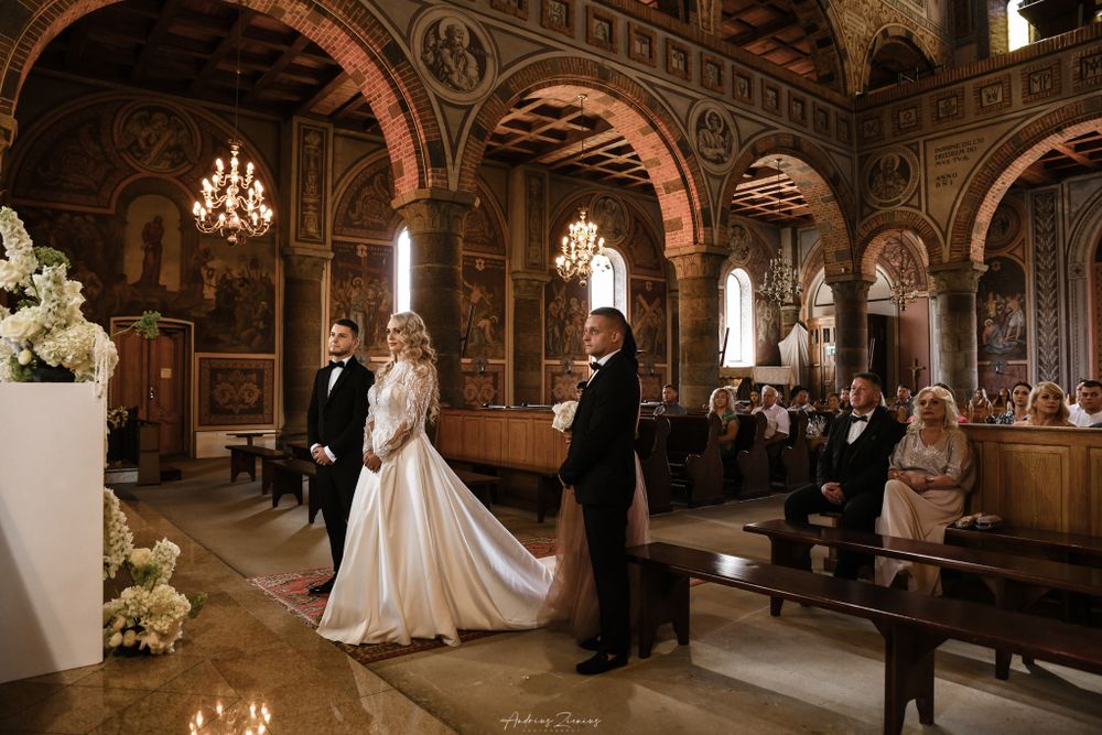 Wedding ceremony in ornate church with arched ceilings and chandeliers.