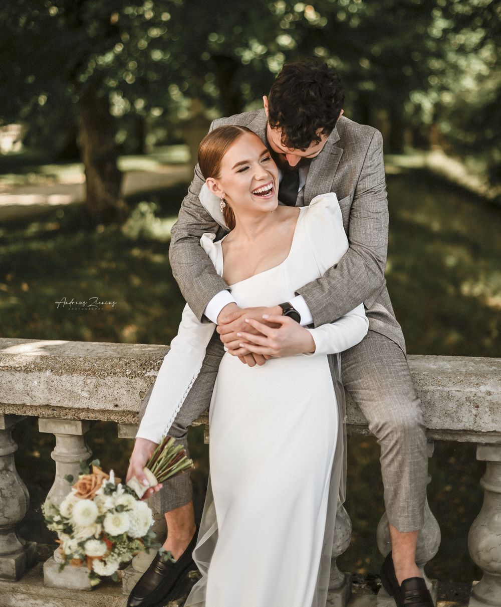 A joyful couple embraces and laughs together during their outdoor wedding photoshoot.