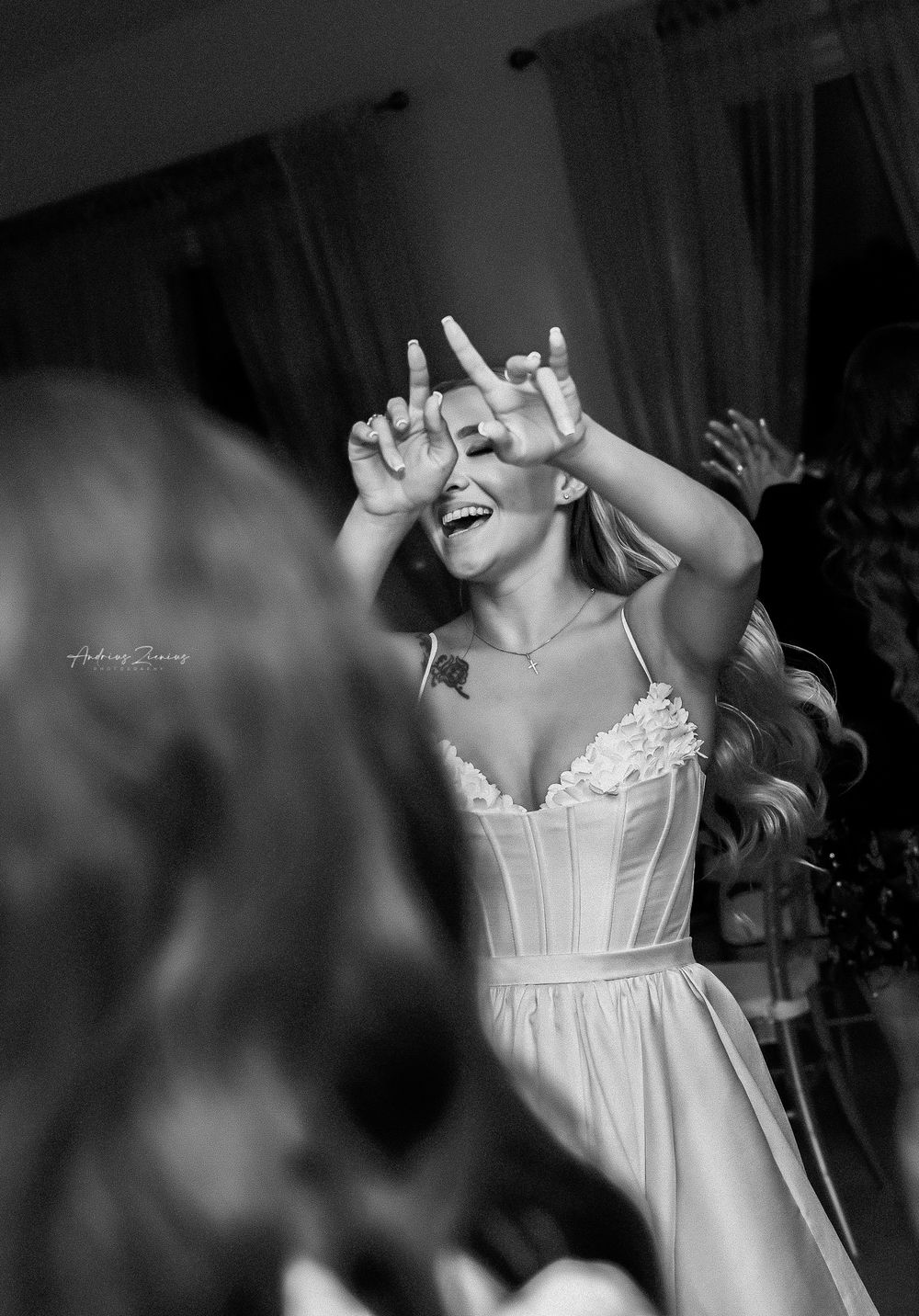 Person in white dress dances joyfully with raised hands at celebration.