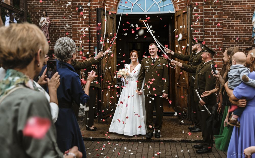 Newlyweds exit church under shower of confetti surrounded by celebrating guests.
