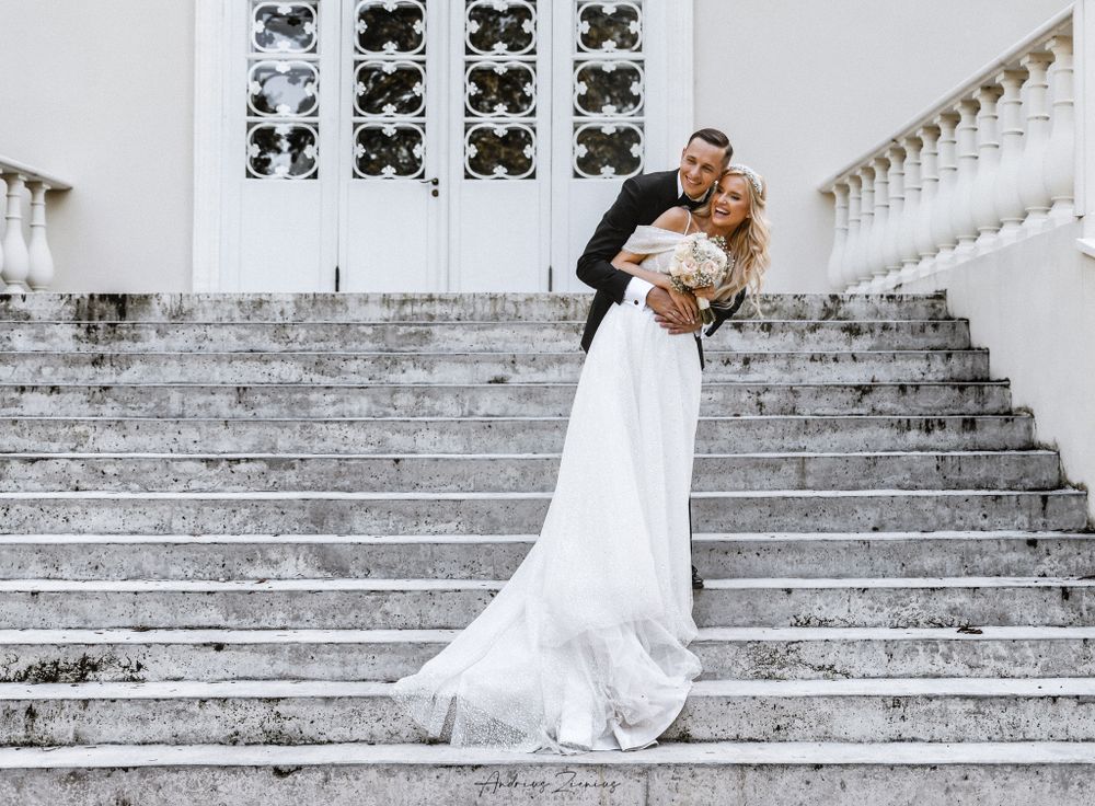 A couple poses dramatically on white marble stairs for their wedding portrait.