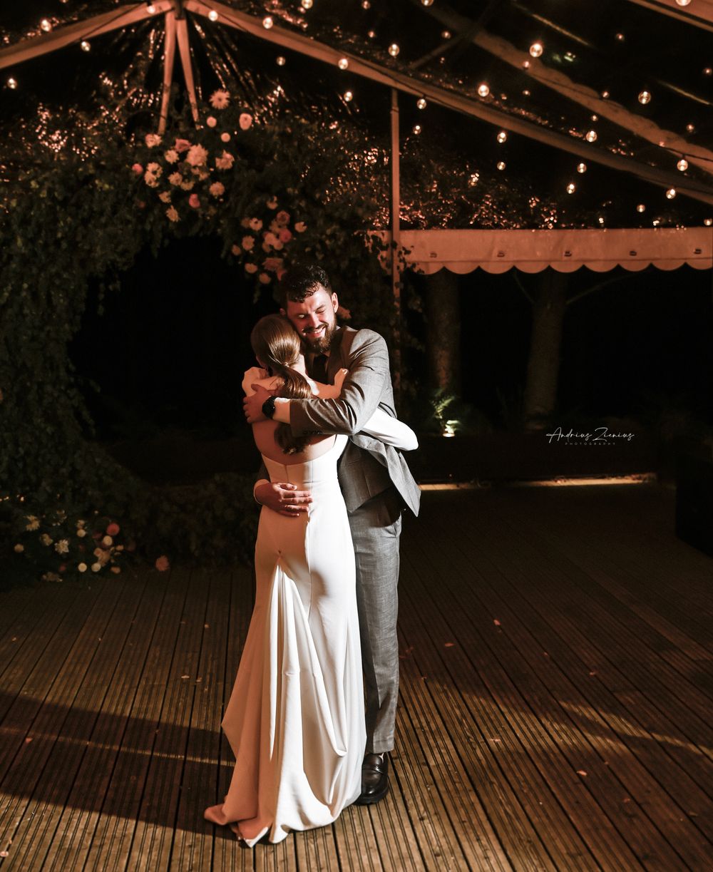 Romantic couple embracing under twinkling lights during their evening reception.