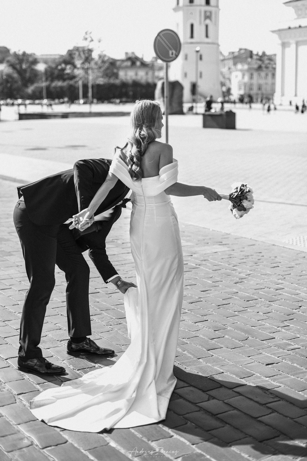 Black and white photo of couple in wedding attire against a cathedral backdrop.