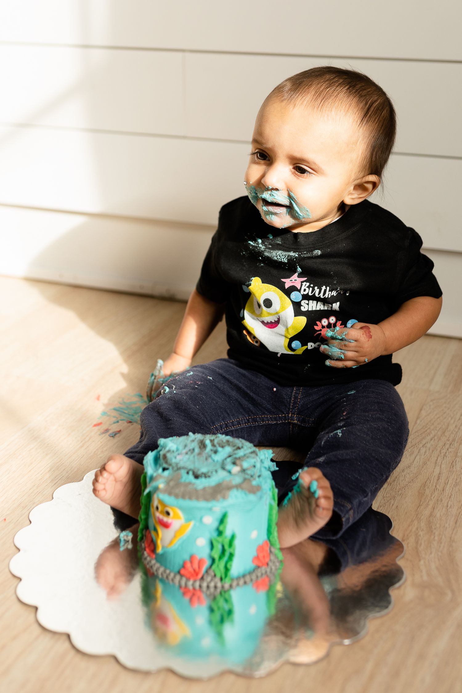 A cake smash photoshoot with turquoise frosting and colorful decorations.