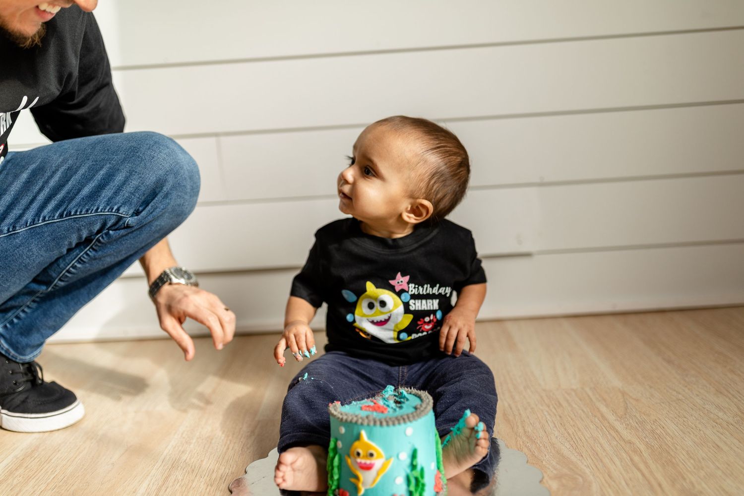 Child in black t-shirt reacting with excitement to teal decorated container.