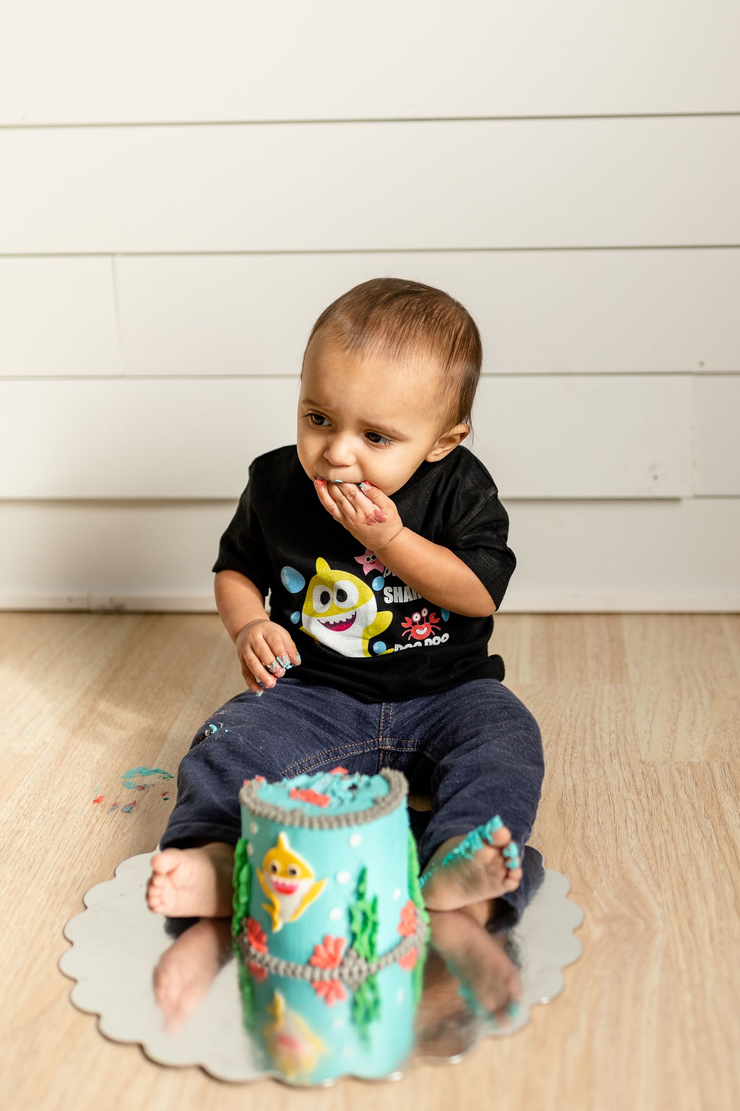 Young child in black shirt covering mouth while looking at decorated container.