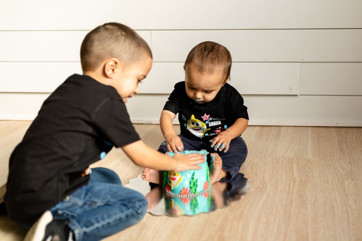 Children sitting on hardwood floor sharing an interactive toy.