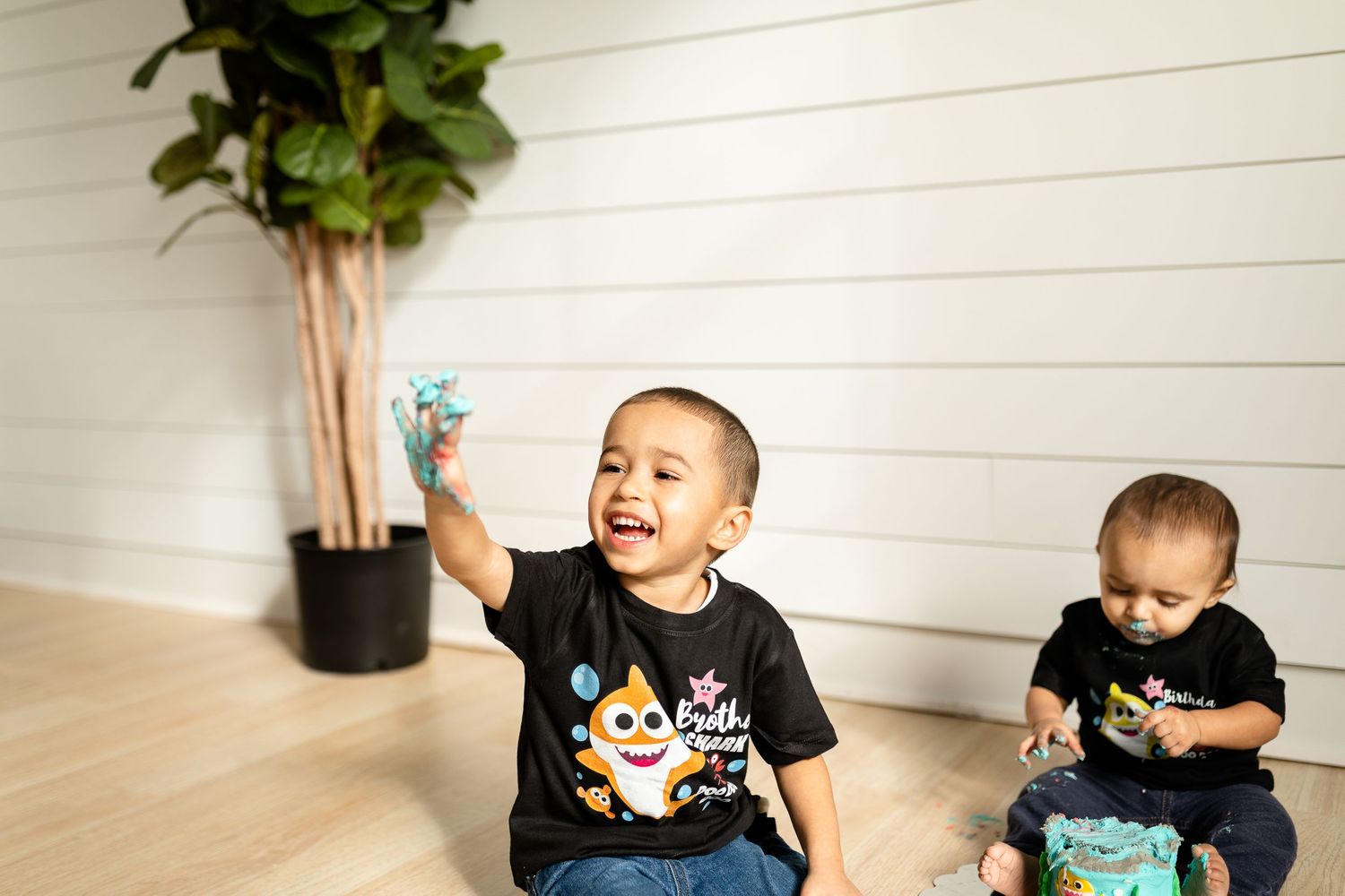 Children laughing while playing with a colorful interactive toy on wooden flooring.