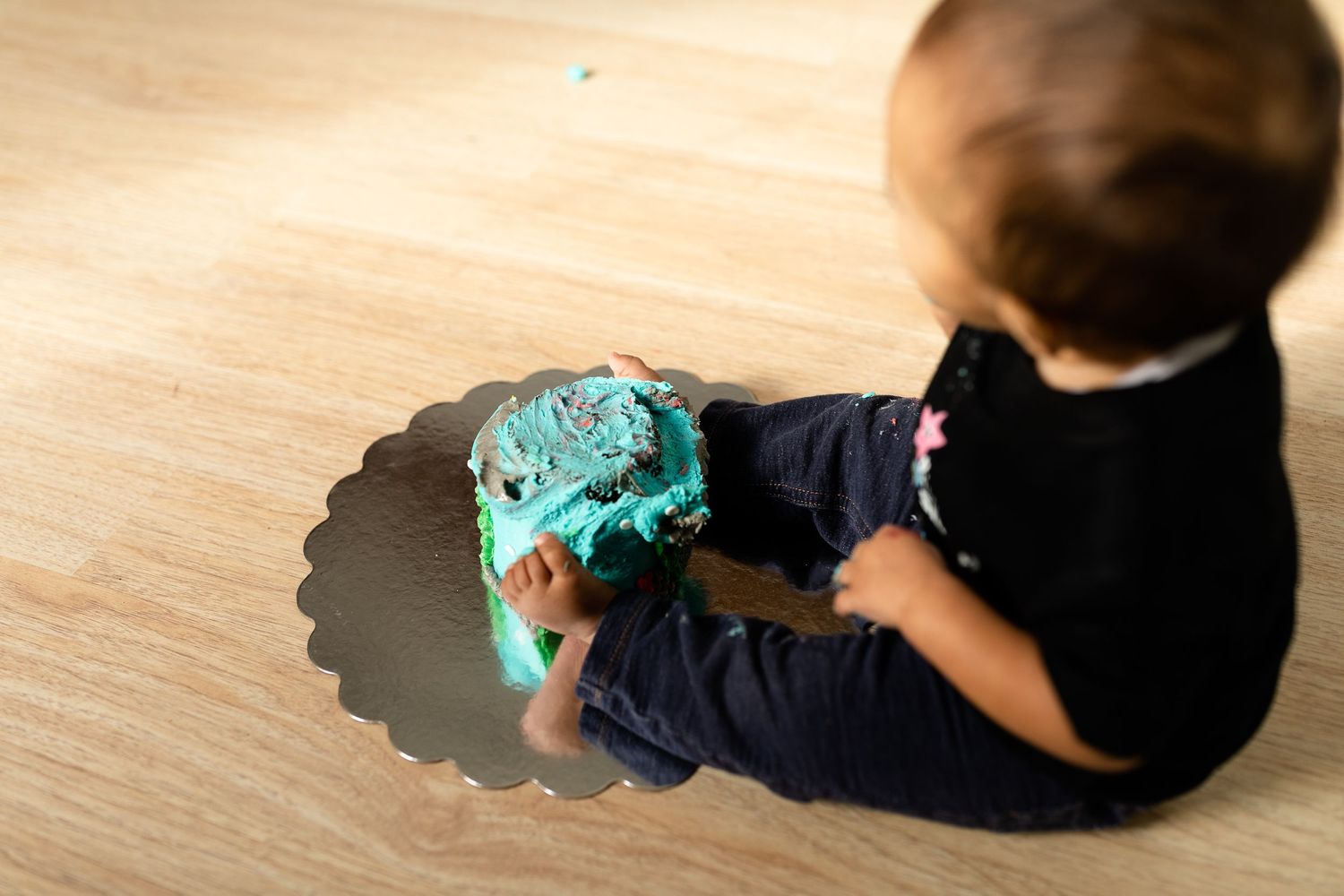 Side view of children playing with bright blue toy on wooden floor.