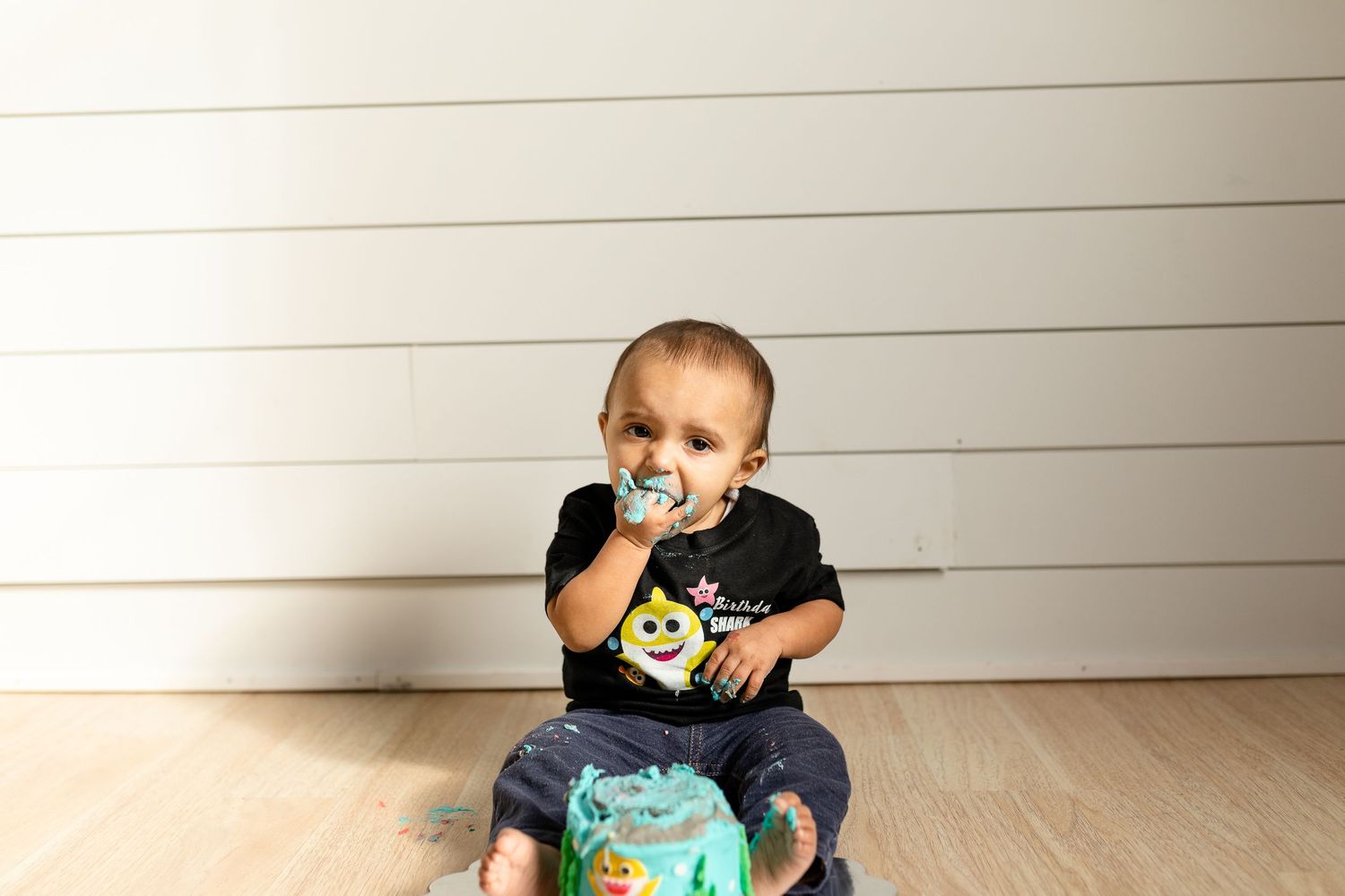 Two kids enjoying playtime with interactive blue toy by white wall.