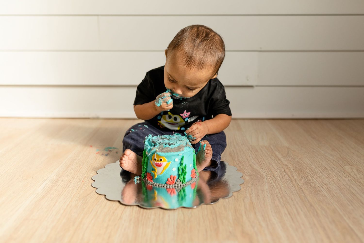 Kids playing together with bright blue interactive toy on hardwood floor.