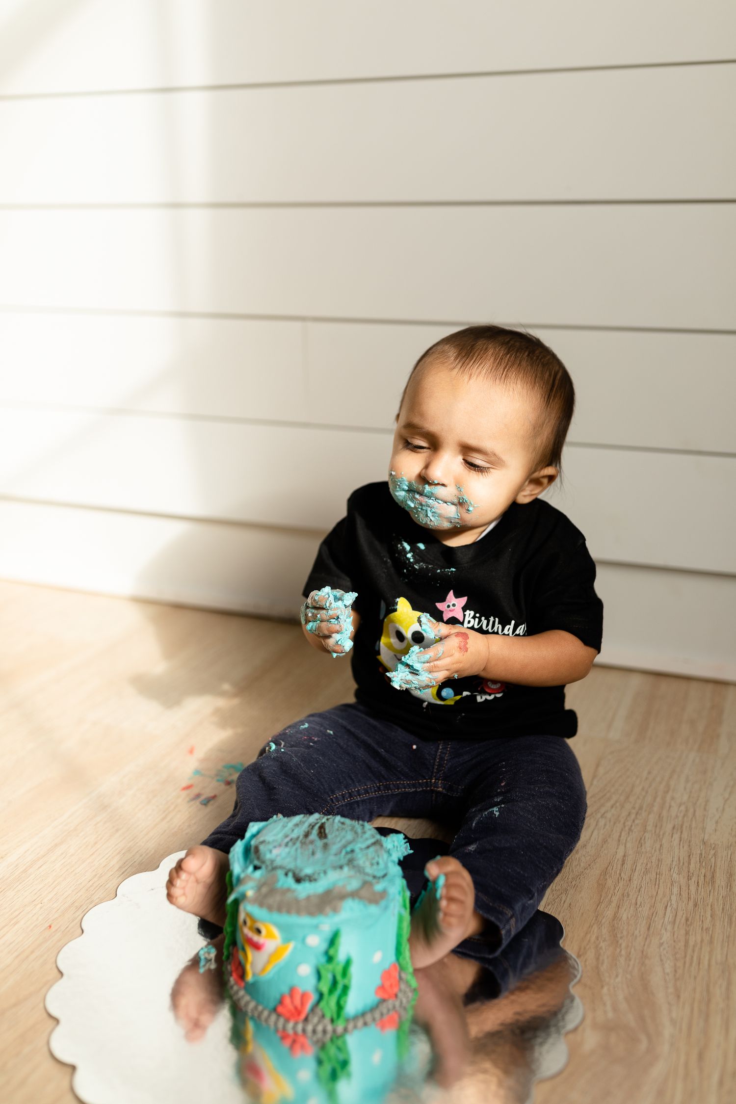 A messy cake smashing session with turquoise frosting on a decorative plate.