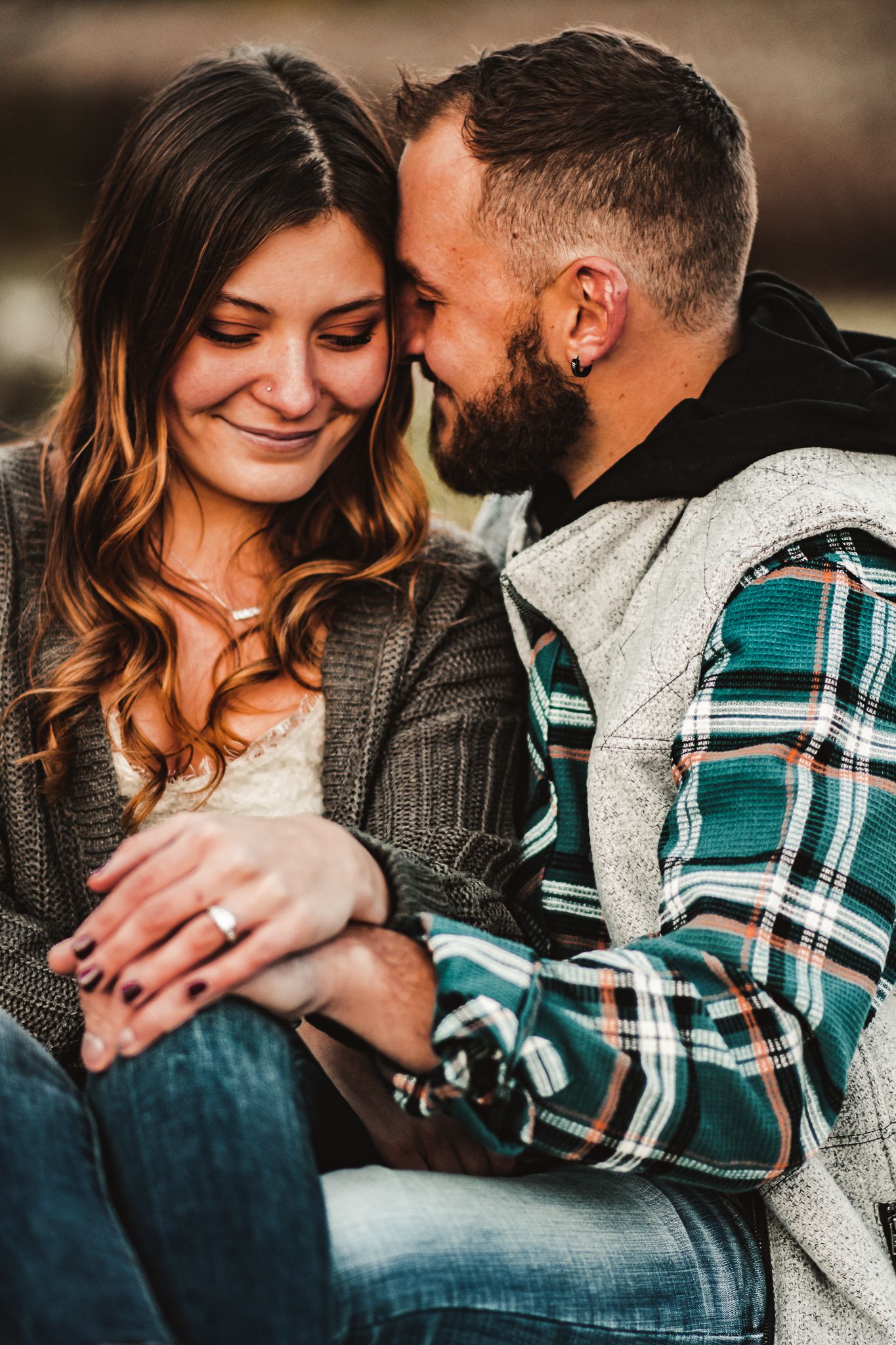 Intimate engagement photo of couple in casual wear sharing a tender moment.