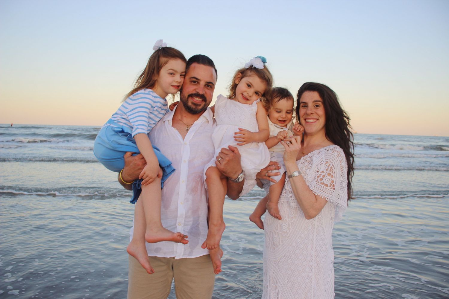 Family of five in front of the ocean at sunset