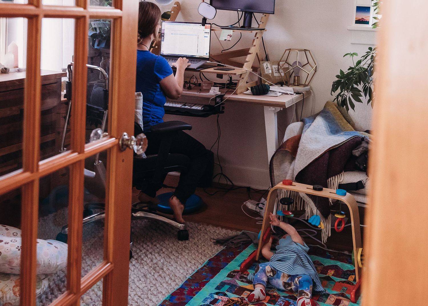 Home office workspace with desk setup viewed through French doors.