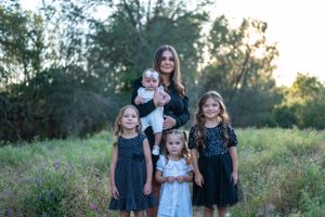 Outdoor family photography featuring children in matching navy dresses at dusk.