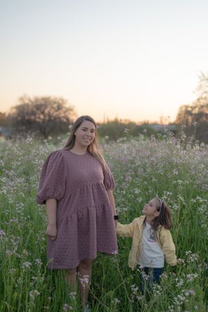 Mother and child walking through a blooming wildflower meadow at sunset.