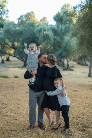A joyful family moment captured in a sun-dappled olive grove.