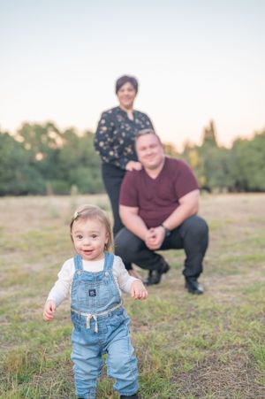Candid outdoor family portrait in a grassy field at sunset.